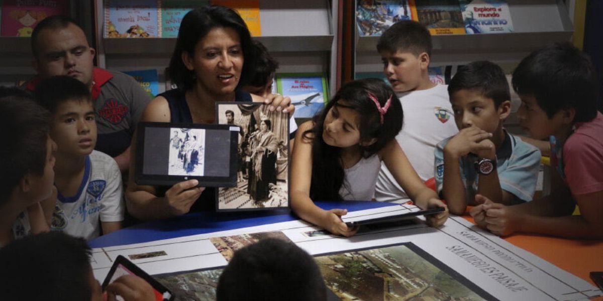 A woman showing pictures to a group of children