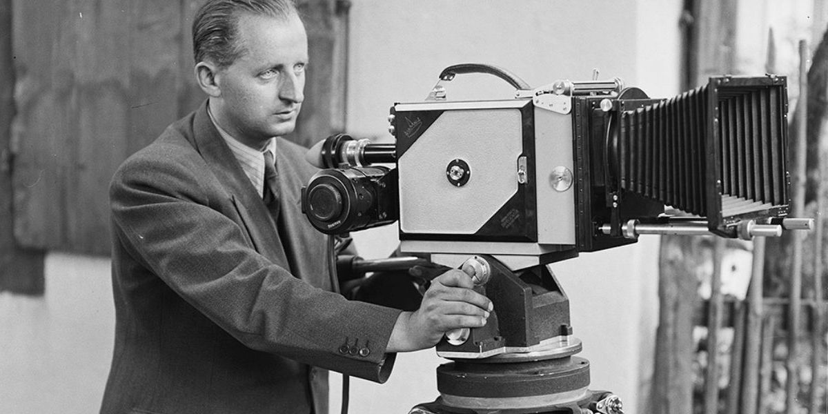 A man stood behind an old-fashioned film camera