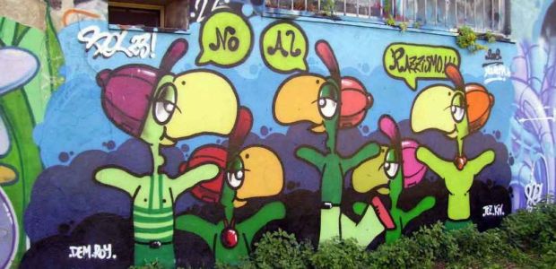 Graffiti of colourful birds, dressed as people. Speech bubbles say 'No al razzismo'