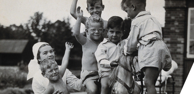 Children playing on a rocking horse with a nurse attending