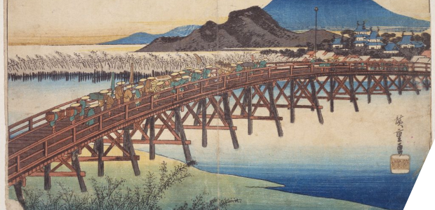 A wooden bridge over a river with mountains in the distance
