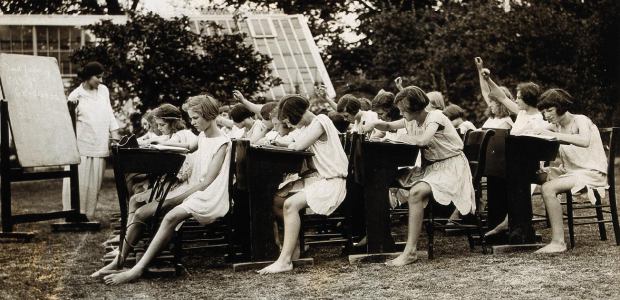 A class of schoolgirls having lessons in the open air, during hot weather