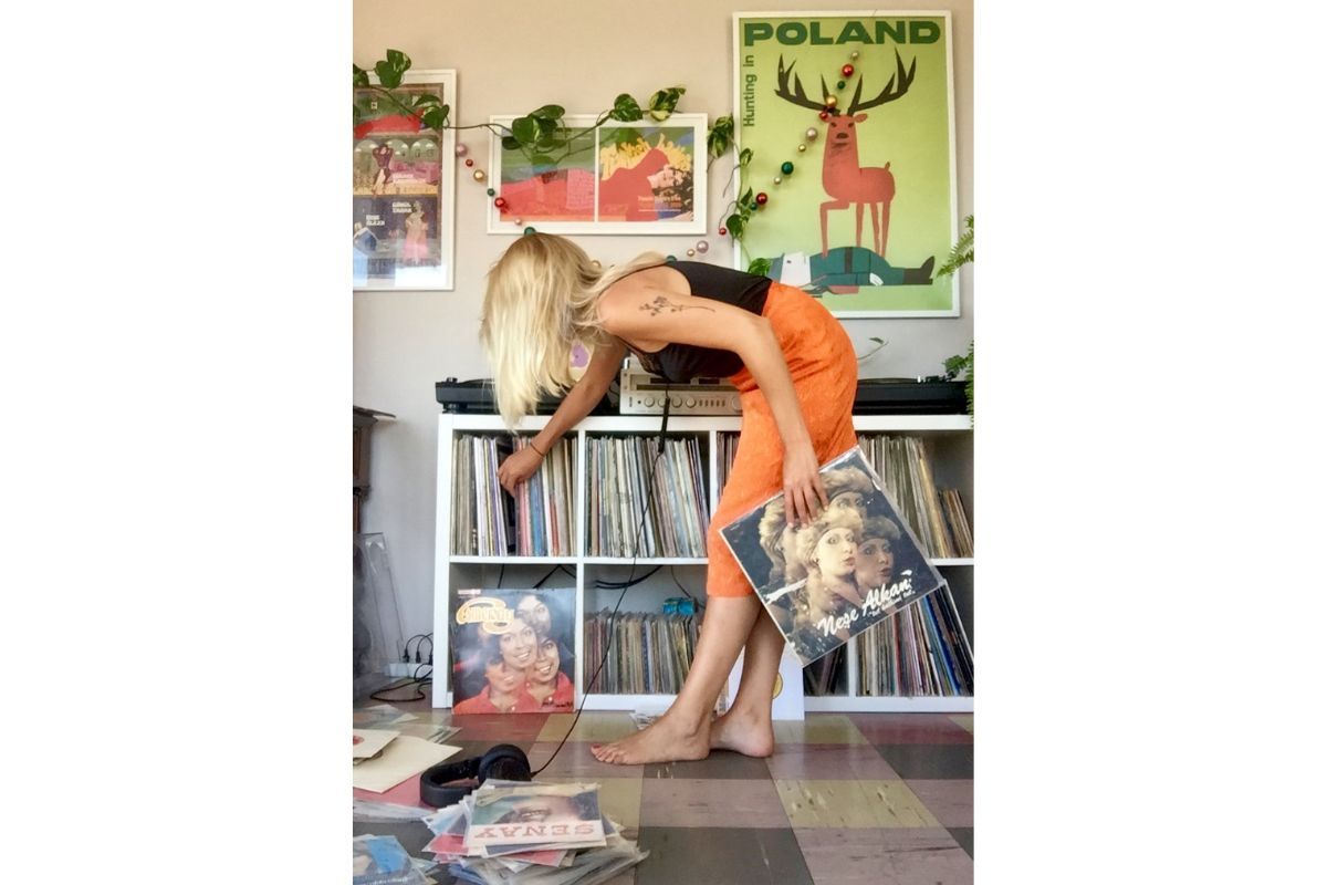 Kornelia leans over to pull a record from a shelf. 