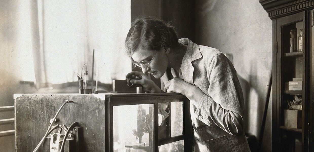 A woman inspecting a microscope in a tank