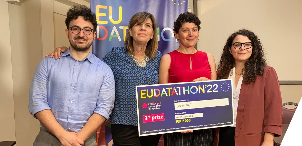Four people stand holding a large piece of card which says EU Datathon 22