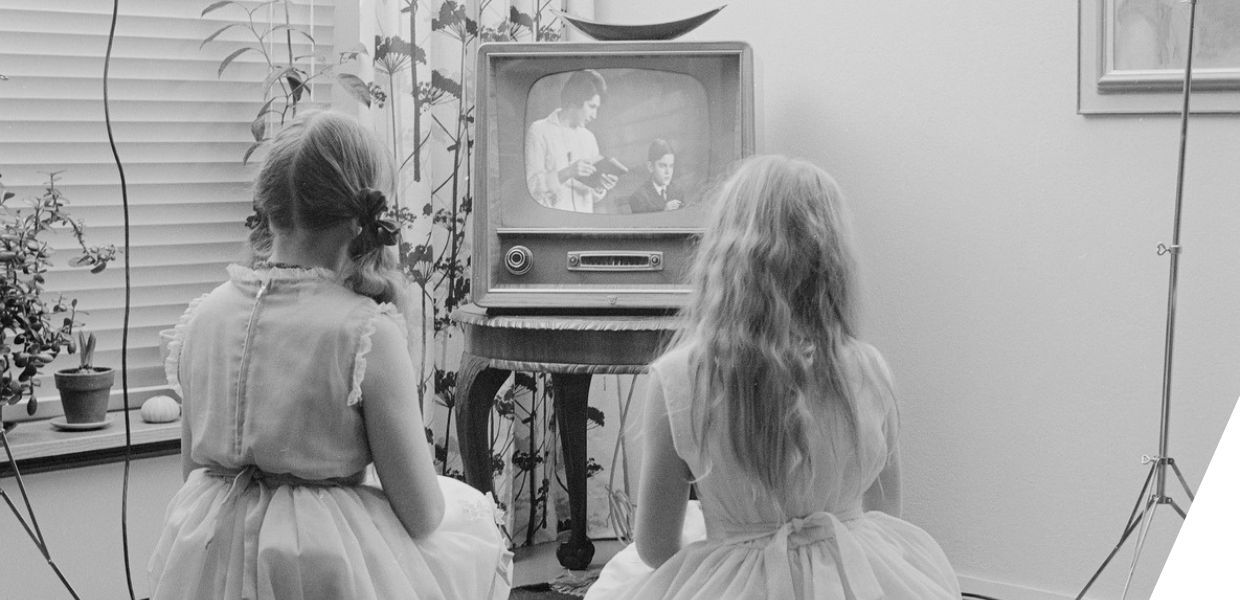 Two young children sit watching television