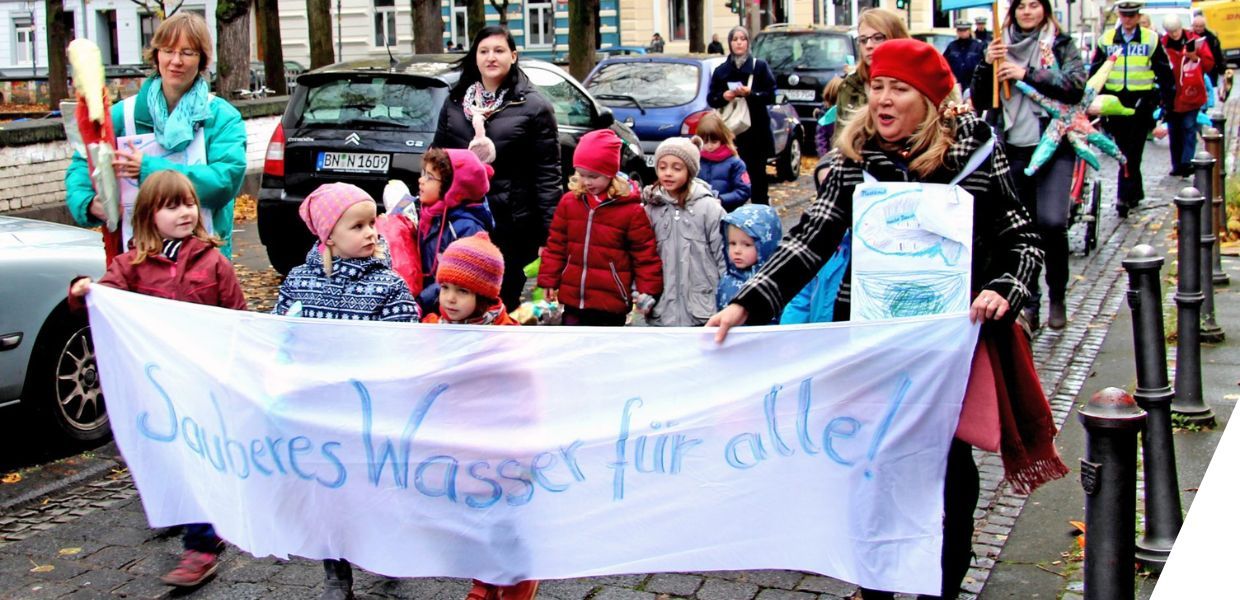 Children's march in a street holding a sign that says sauberes wasser fur alle!
