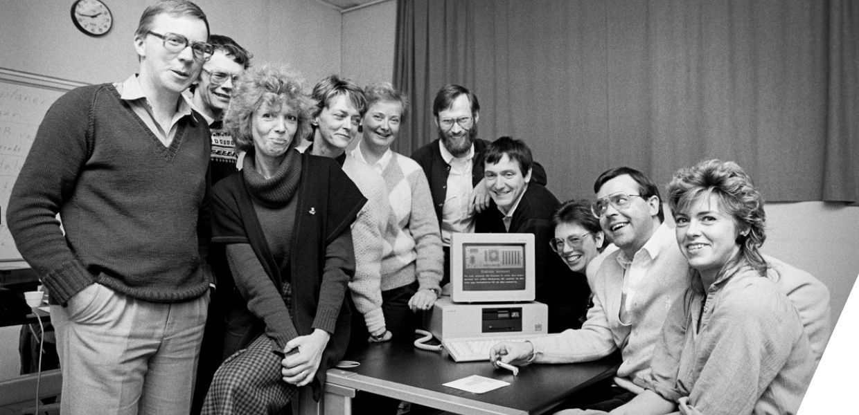 A group of people sat around a computer, smiling