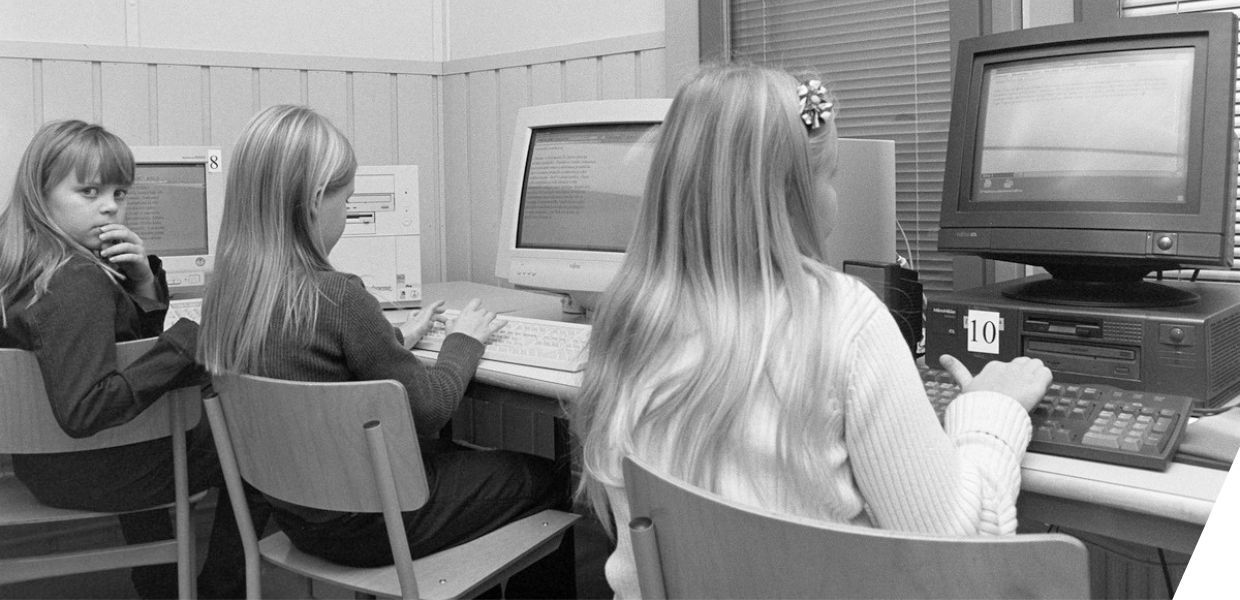 Three young girls sat in front of computers in IT class