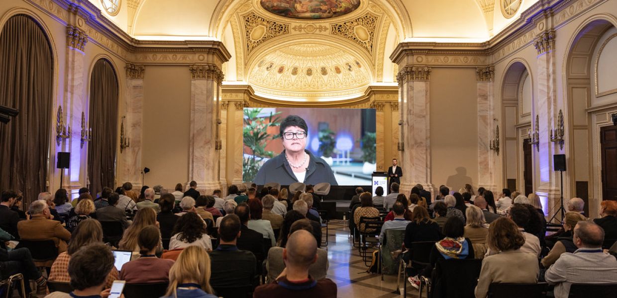 People watching an on screen video message from Sabine Verheyen, Vice-President of the European Parliament. 