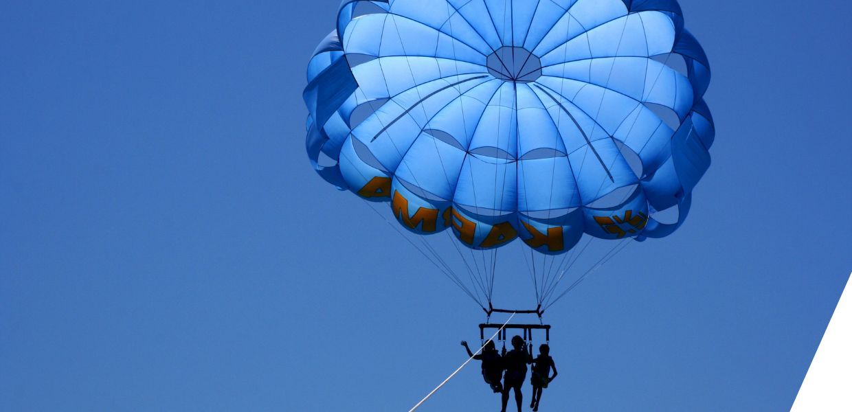 Three people sat under a large balloon, silhouetted against a clear blue sky